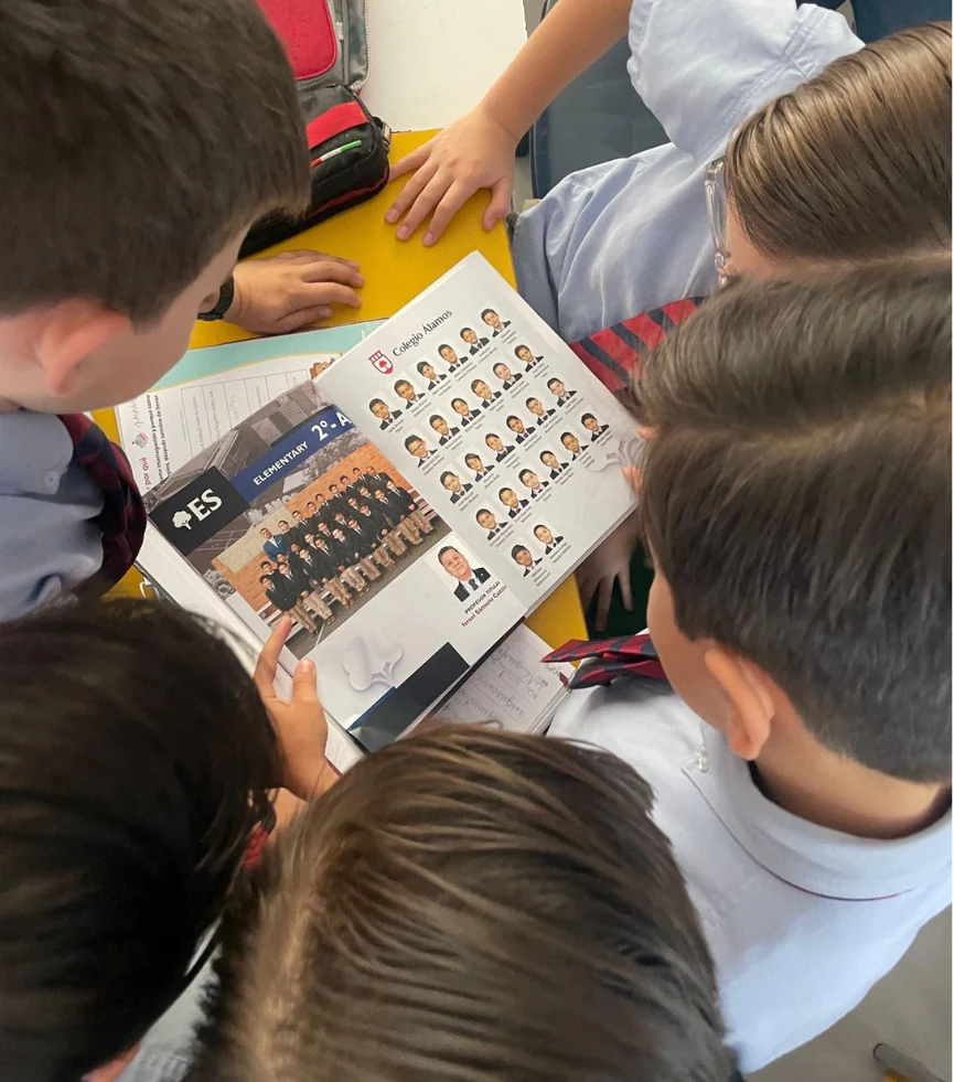 Grupo de alumnos observando juntos un anuario escolar abierto
